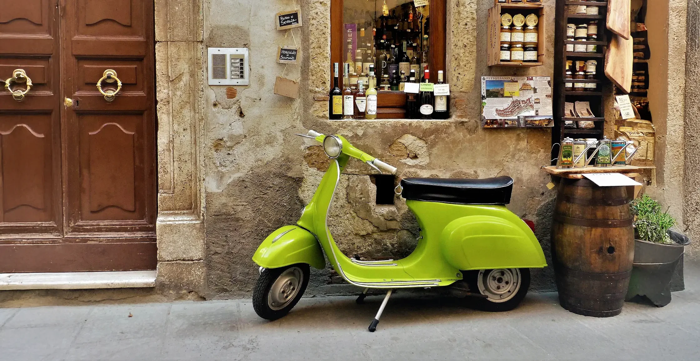 Una moto vespa verde parcheggiata davanti ad una casa in toscana
