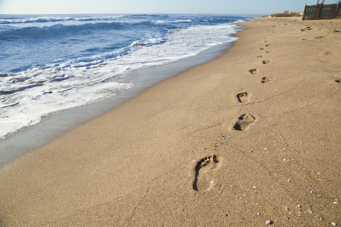 Orme di piedi scalzi sulla sabbia in spiaggia