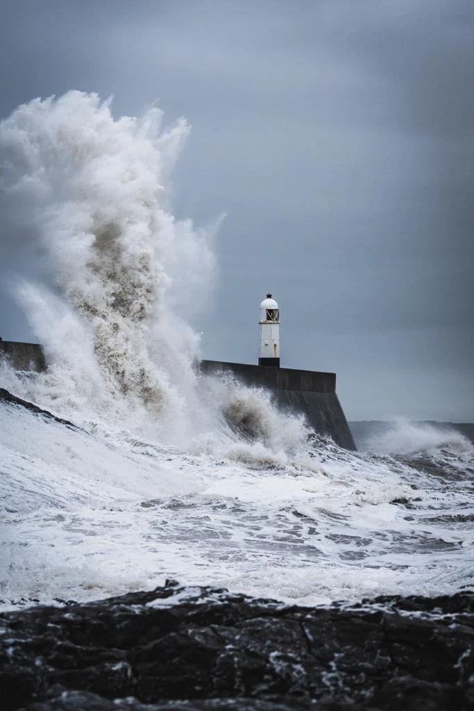 Immagine di un faro con sfondo il mare mosso e cielo nuvoloso