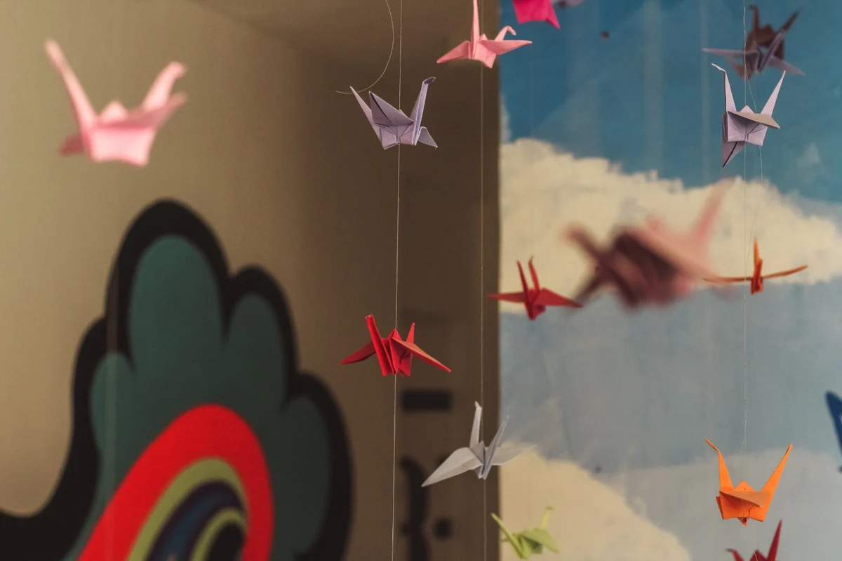Immagine di origami colorati che penzolano dal soffitto, attaccati tutti da un cavo